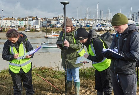 four students in a harbour with clipboards