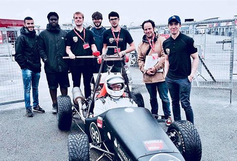 Seven people around a formula racing car