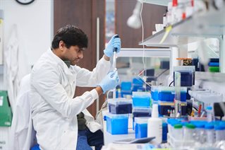 Scientist in a white lab coat testing samples in a lab