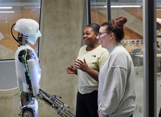 Two students in front of a robot