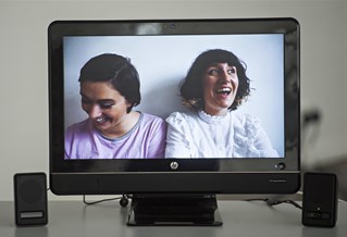 Two people laughing on a monitor