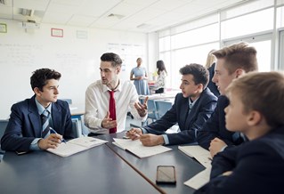 Male teacher sitting with students