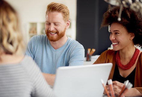 three people laughing round a laptop