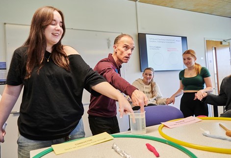 student and lecturer with their fingers in a jug of water