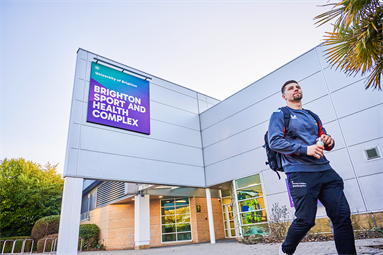 student outside the sport and health complex at Falmer