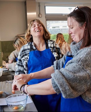 lecturer laughing with student while cooking