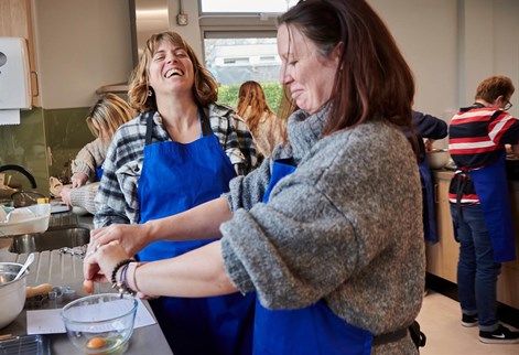 lecturer laughing with student while cooking