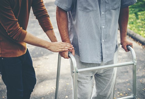 man being shown how to use a walking frame