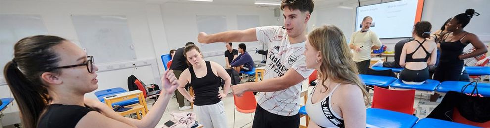 group of students round another on a physio couch