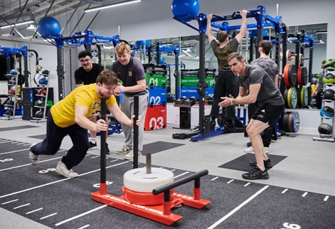 student pushing weights in the S&C suite