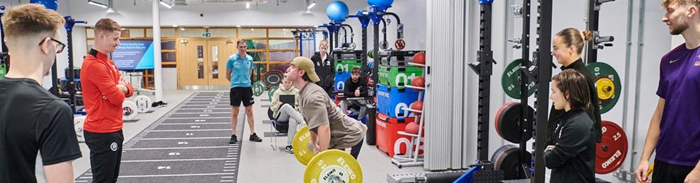 students lifting weights in the strength and conditioning suite