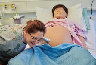 student listening to the mannequins baby's heartbeat