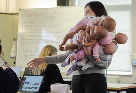 student midwife carrying baby mannequins