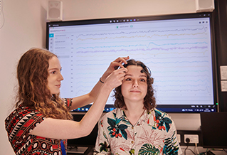 A student putting a brainwave monitor on another student