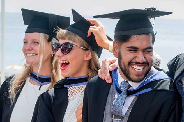 A group of graduates by the beach