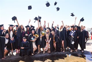 A group of graduates throwing mortar boards in the air