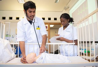 Two Brighton nursing students practising on a dummy baby