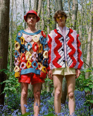 Two people in shorts and bright tops standing in a forest