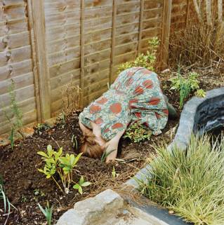 Woman burying her head in a garden