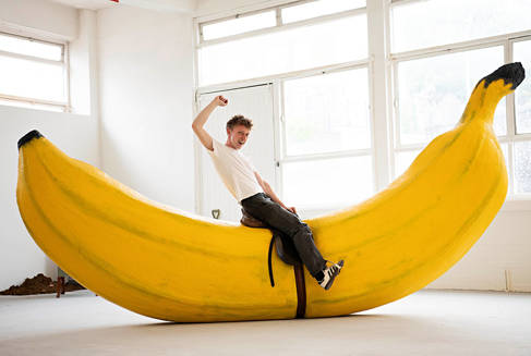 Student sitting on a saddle strapped to a oversized banana