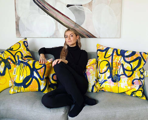 Freya Richmond on a plain sofa with graffiti inspired cushions